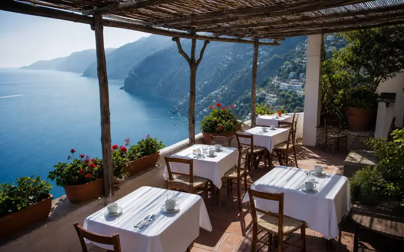 Breakfast terrace over the sea with a reed pergola and linen-clothed tables